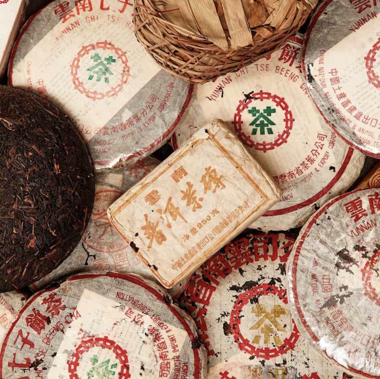 A stack of aged pu-erh tea cakes with original wrappers